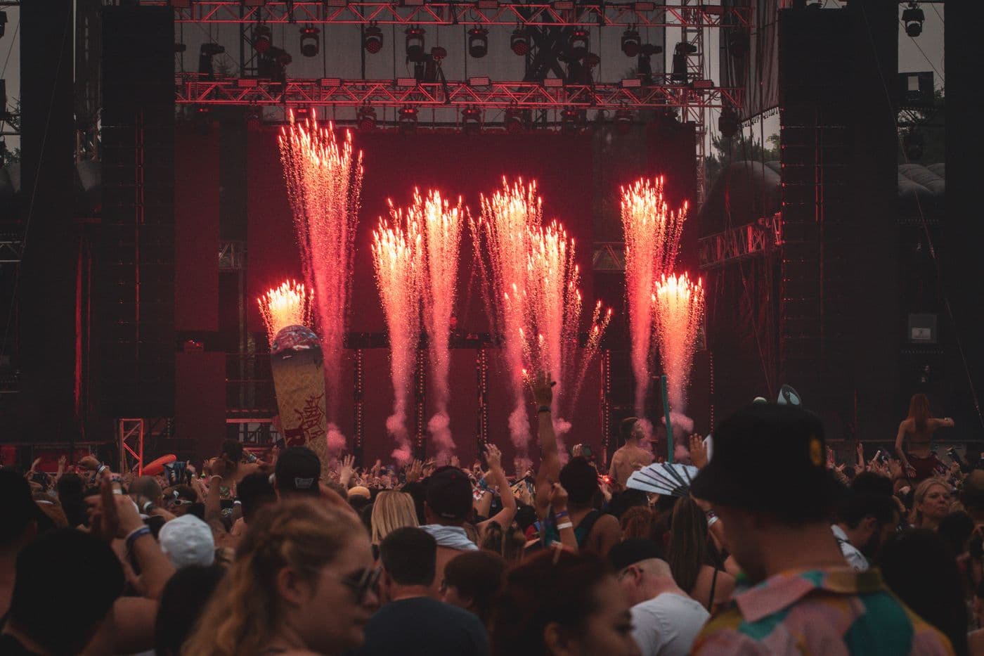 Red fireworks bursting over a crowd with hands in the air